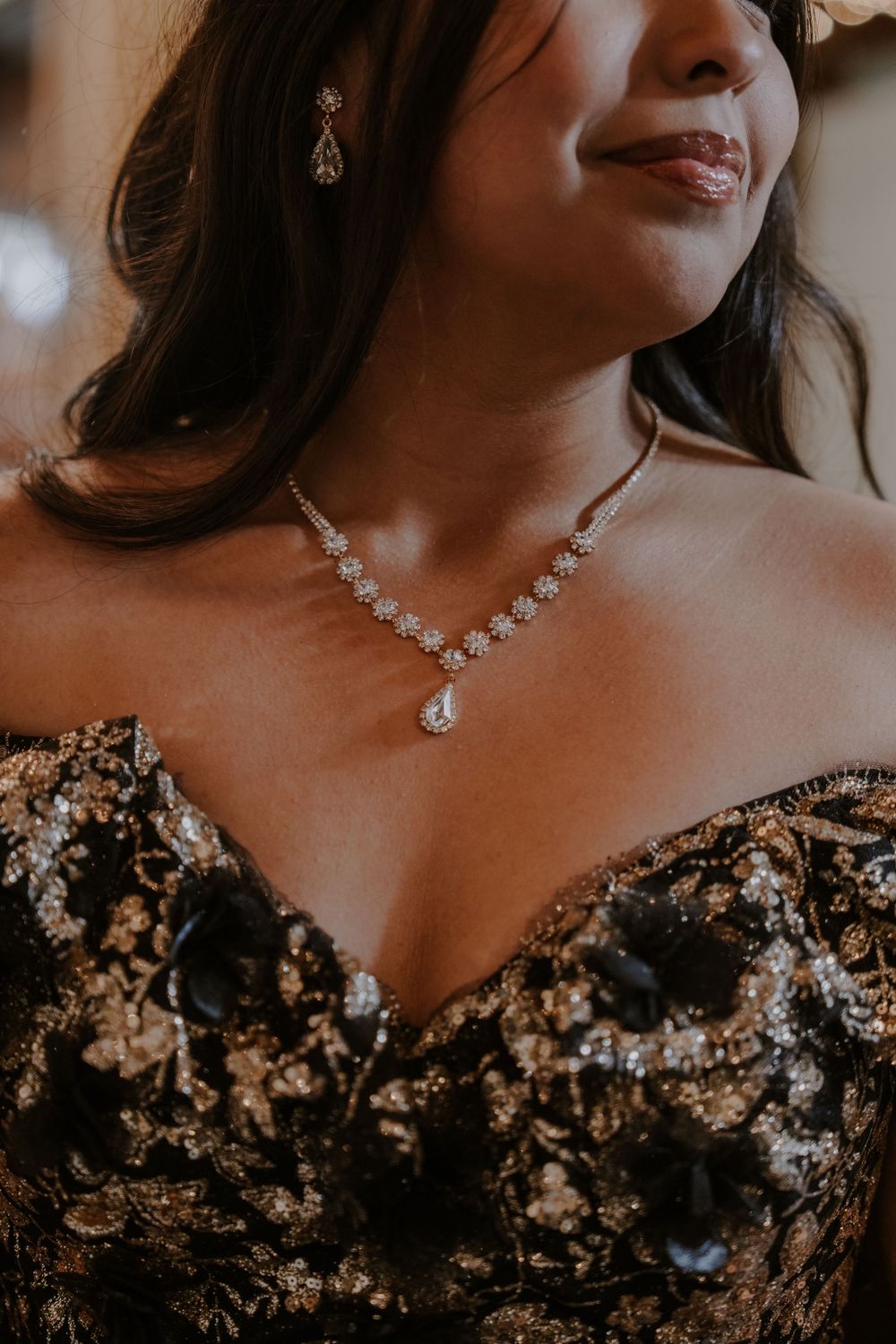 Elegant crystal necklace and earrings set against a black and gold embellished dress.
