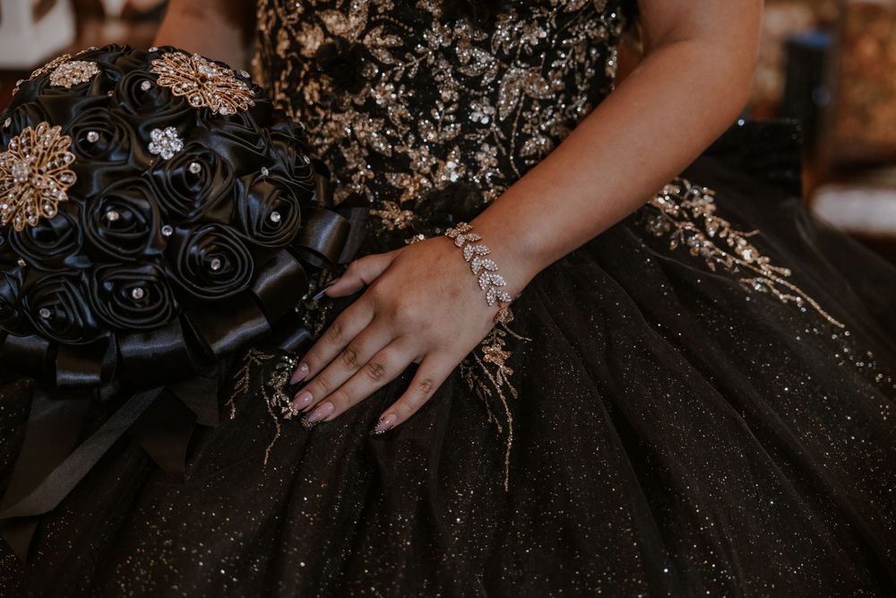 Close-up of a black ball gown with gold details and floral embellishments.