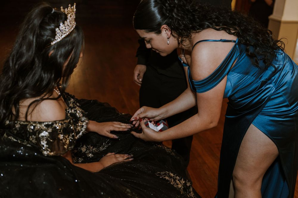 Helping adjust details on an ornate black and gold ball gown during a special celebration.