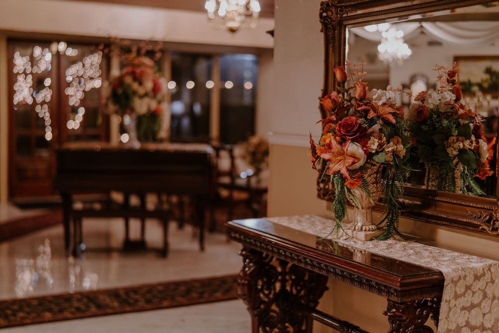 Elegant dining room with ornate mirror, crystal chandelier and floral arrangements.