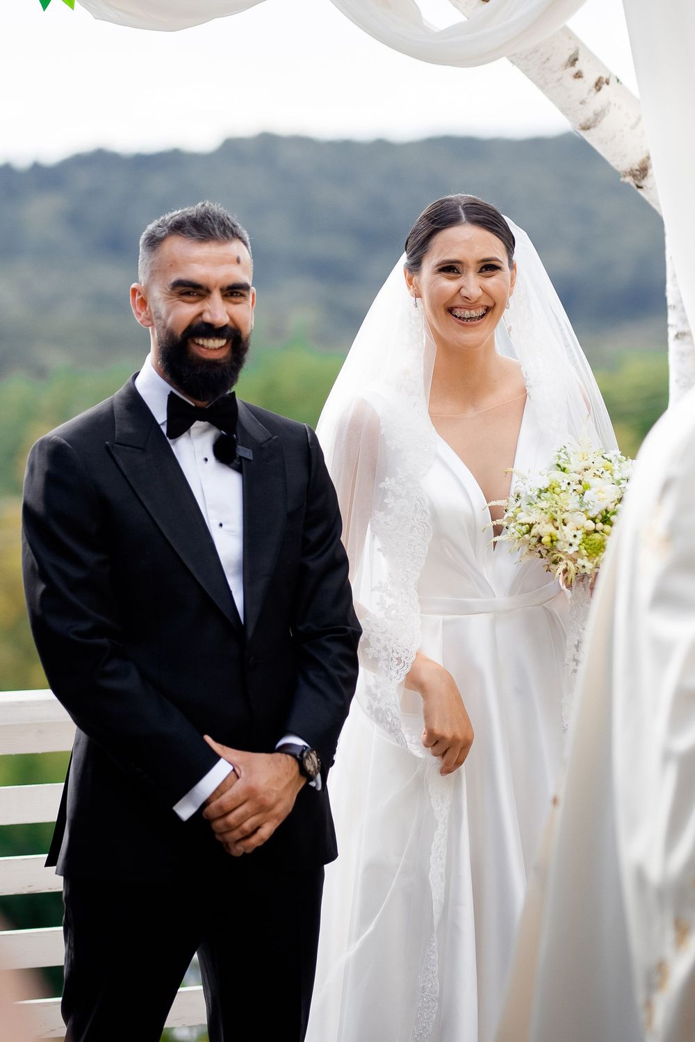Wedding ceremony on an outdoor terrace with white draping and mountain views in the background.