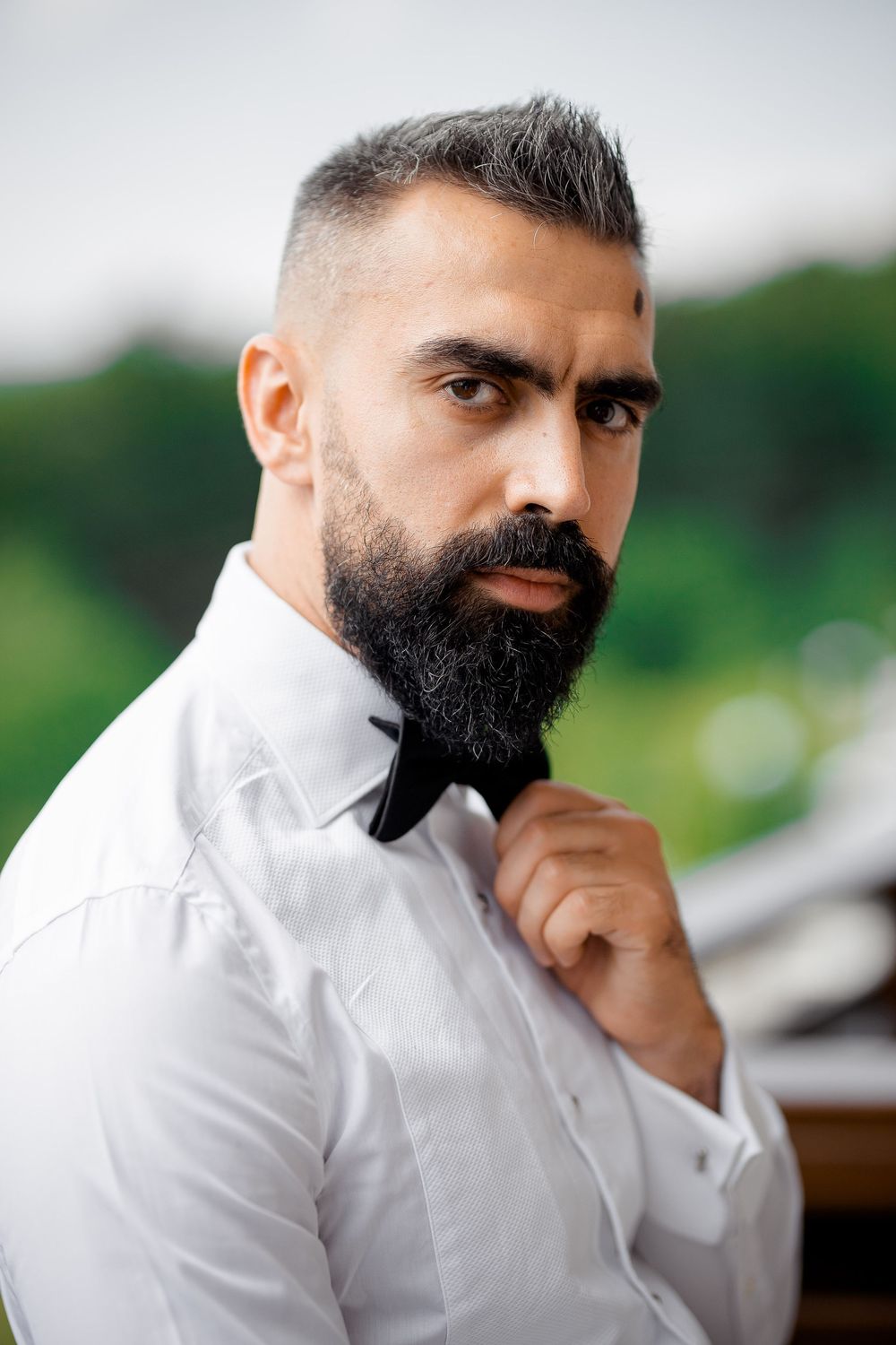 Close-up portraits of a bearded man in a white shirt looking thoughtful against a blurred background.