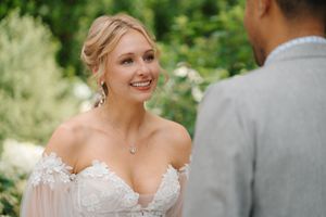 A romantic wedding moment captured outdoors with soft natural lighting and greenery in the background.