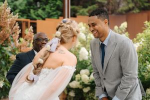 A joyful moment shared between a bride in a flowing dress and groom in a gray suit during an outdoor garden wedding ceremony.