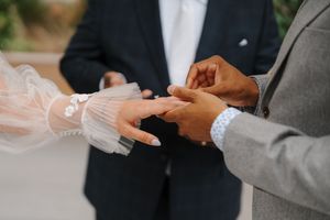 Close-up view of hands exchanging wedding rings during a traditional ceremony.