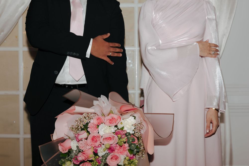 A bride and groom share a tender moment during their wedding ceremony in an elegant white room.