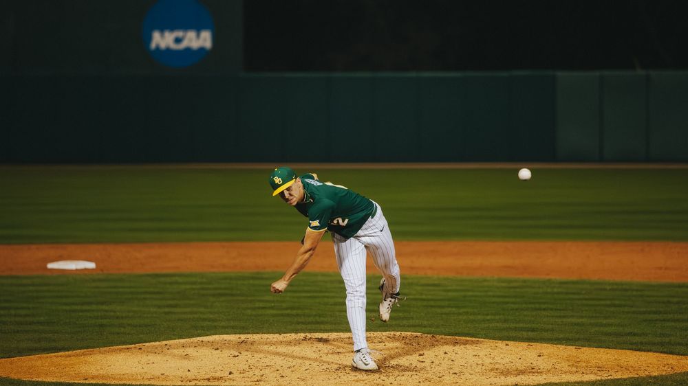 Baylor Bears baseball pitcher delivers a pitch during an NCAA college baseball game under the lights.