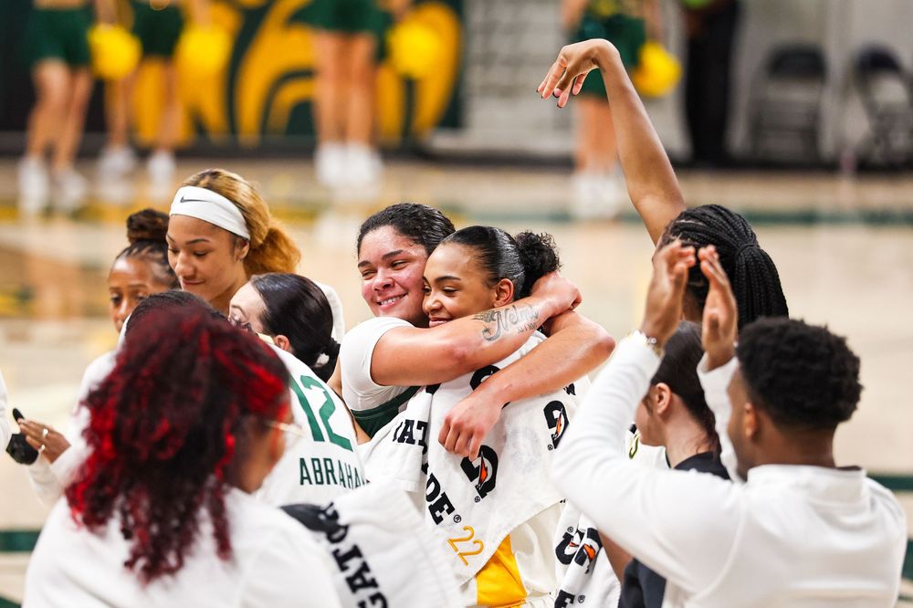 Baylor Bears women's basketball team celebrating together in group hug on the court after victory.
