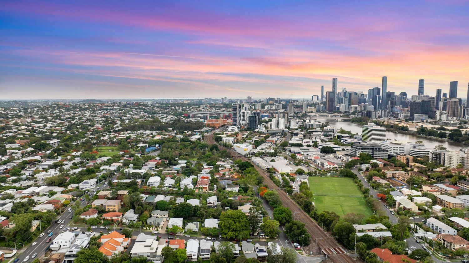 Stunning panoramic cityscape at sunset with vibrant purple and orange sky.