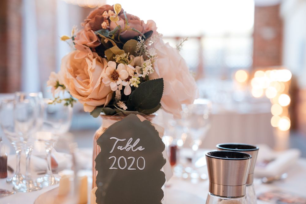 Elegant wedding reception table settings with blush pink floral centerpieces and romantic candlelight decor.