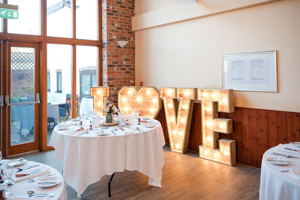 Panoramic view of an elegant restaurant interior with exposed brick walls, white tablecloths, and warm lighting.