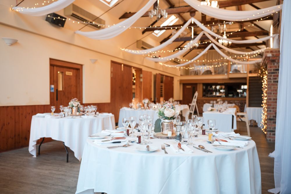 A rustic wedding reception venue decorated with string lights and white tablecloths for an elegant celebration.