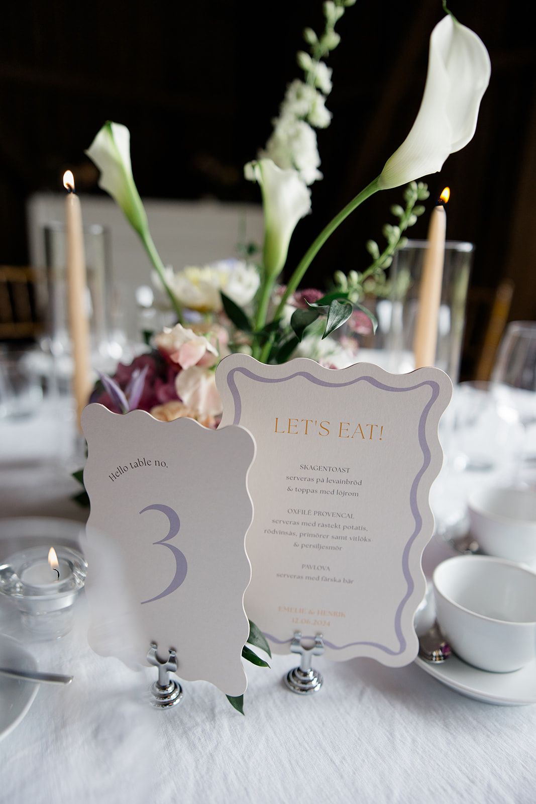 Elegant wedding table setting with white calla lilies and decorative menu cards on crisp white linens.
