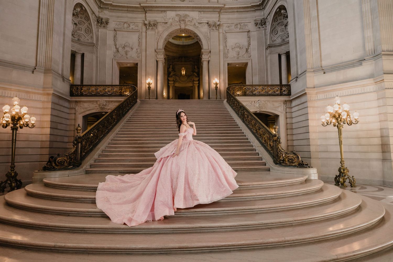 A sweeping view of a classical interior with marble stairs and a flowing pink gown in the foreground.