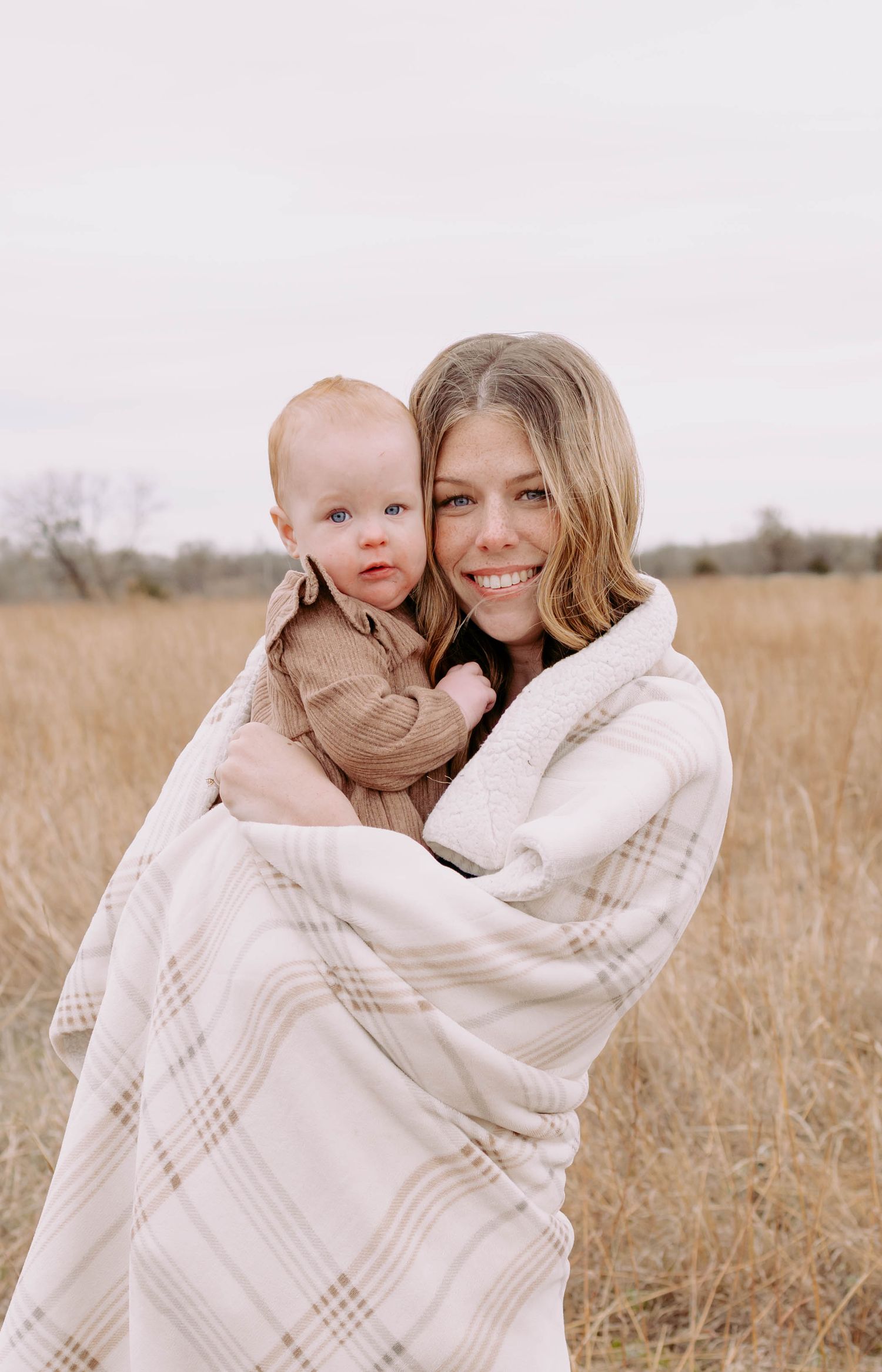 True West Photography - Tender moment of cuddling under a cozy blanket in a golden field.