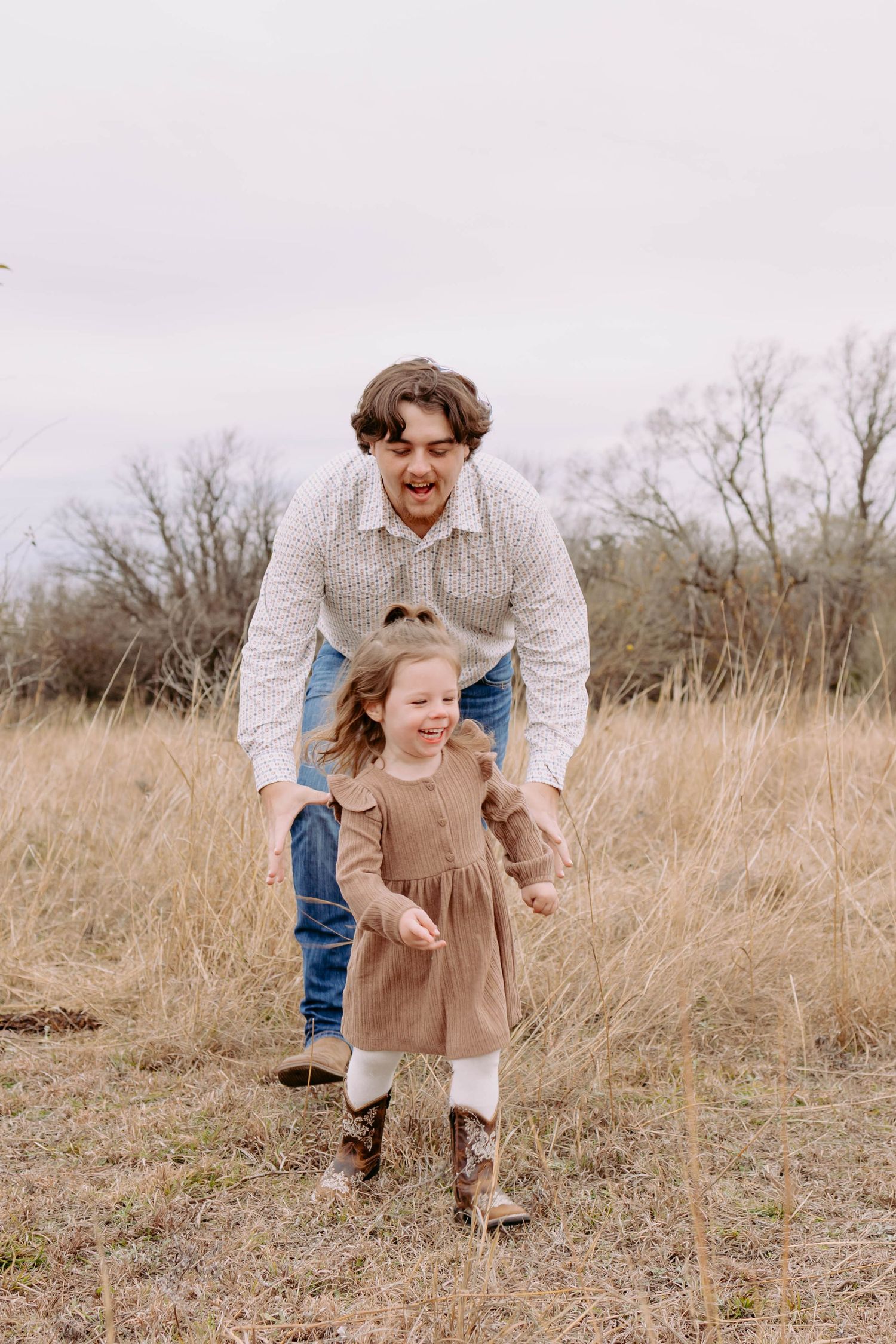 True West Photography - Parent and child sharing joyful moments in a field of tall grass.