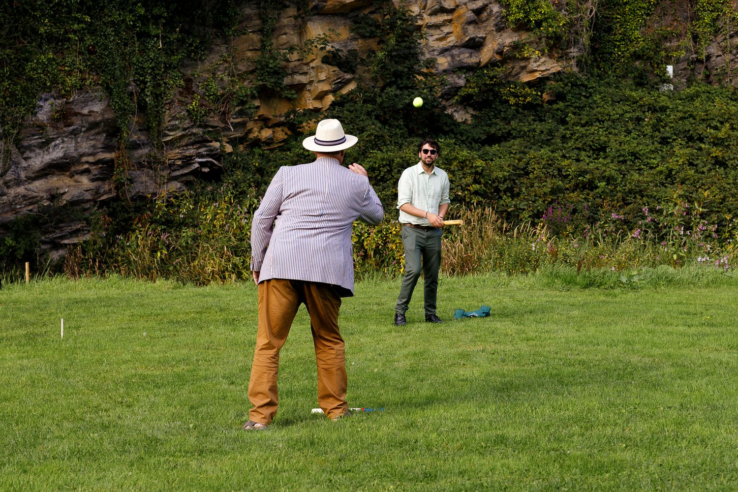 People enjoying a game of disc golf in a grassy field surrounded by trees and forest.