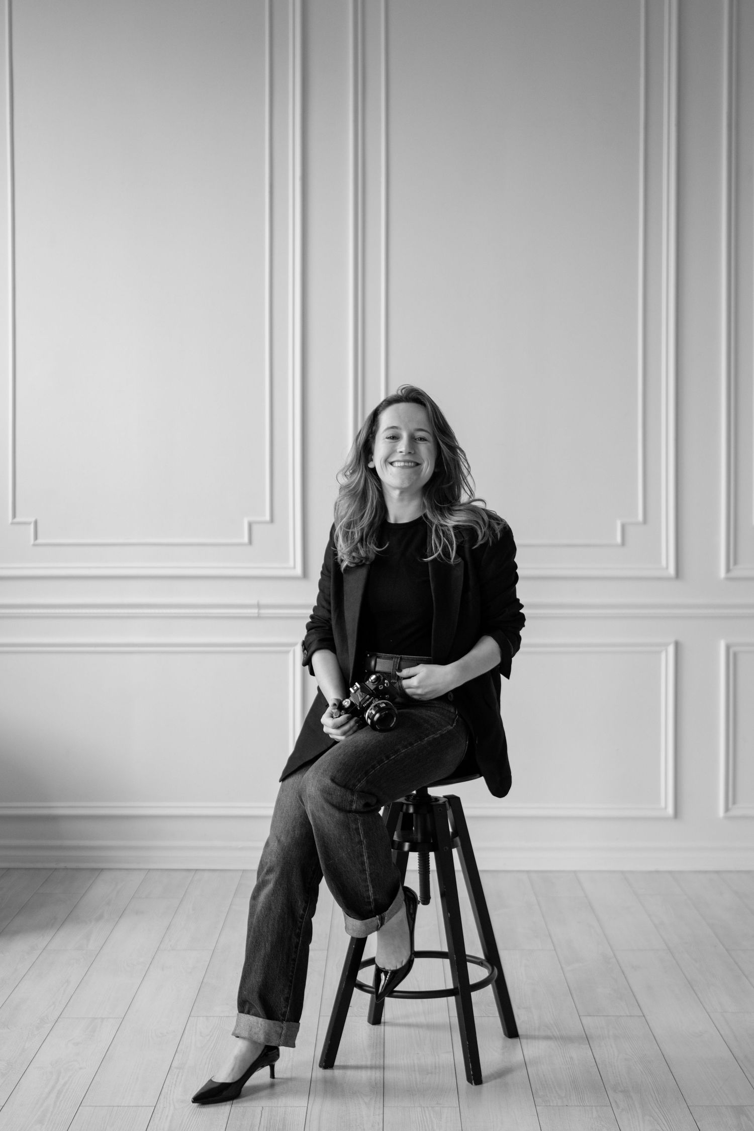 Professional photographer in white outfit sitting on concrete steps with camera.