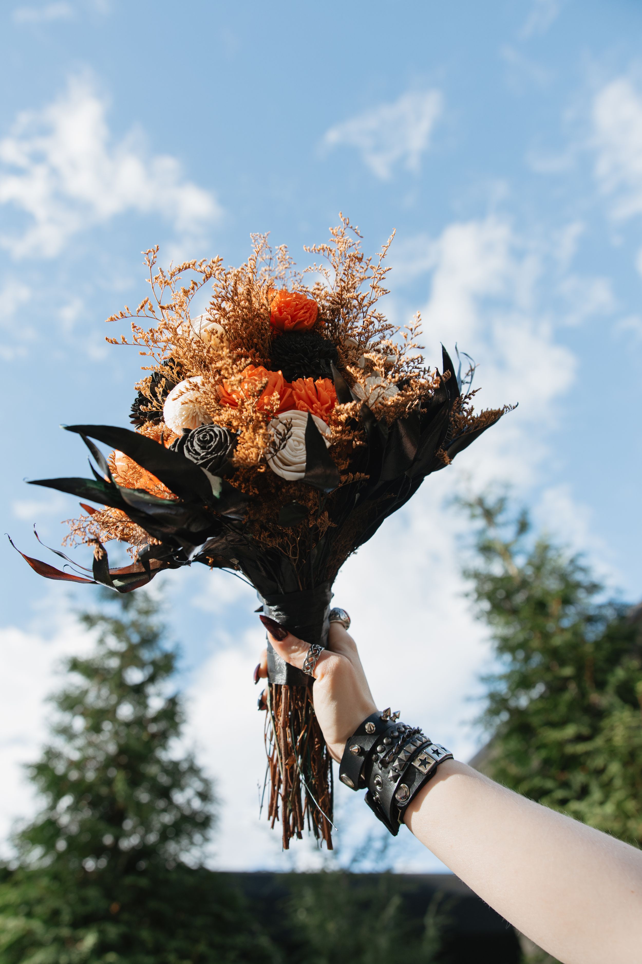 Close-up shots of an ornate orange and black floral crown against a blue sky backdrop.