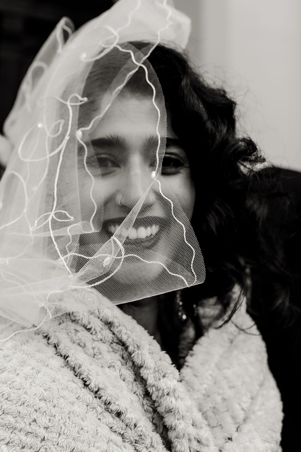 Black and white photo sequence showing joyful expressions and laughter while wearing a fluffy white winter coat.