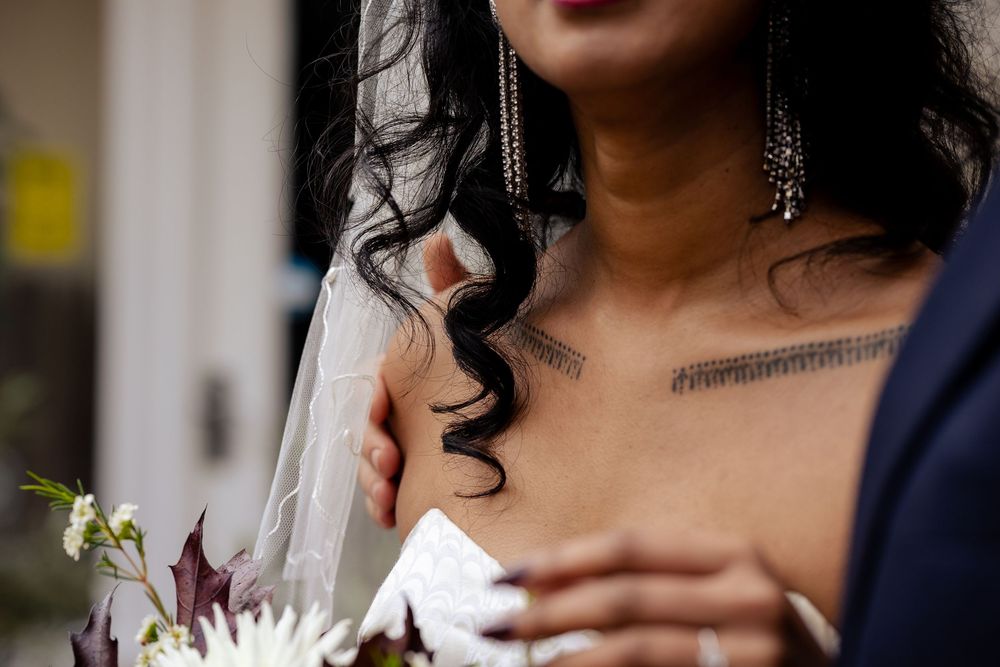 A couple in wedding attire stands close together while holding white floral bouquets.