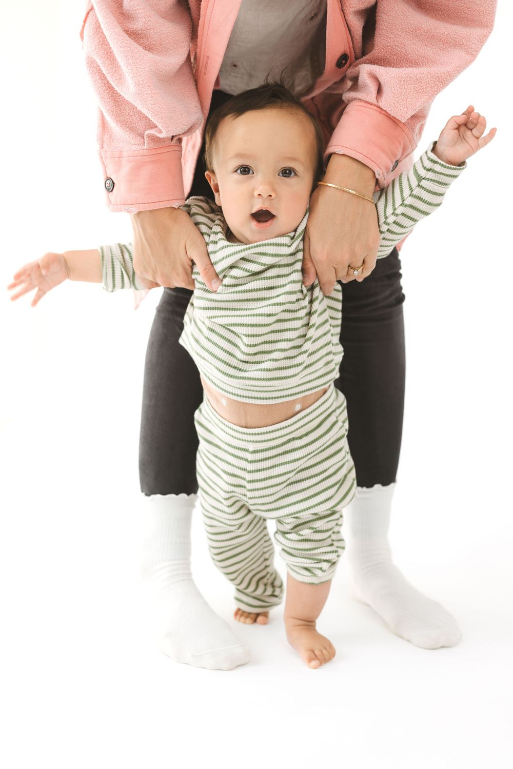 Baby in striped outfit crawling and playing on white background in progressive motion sequence.