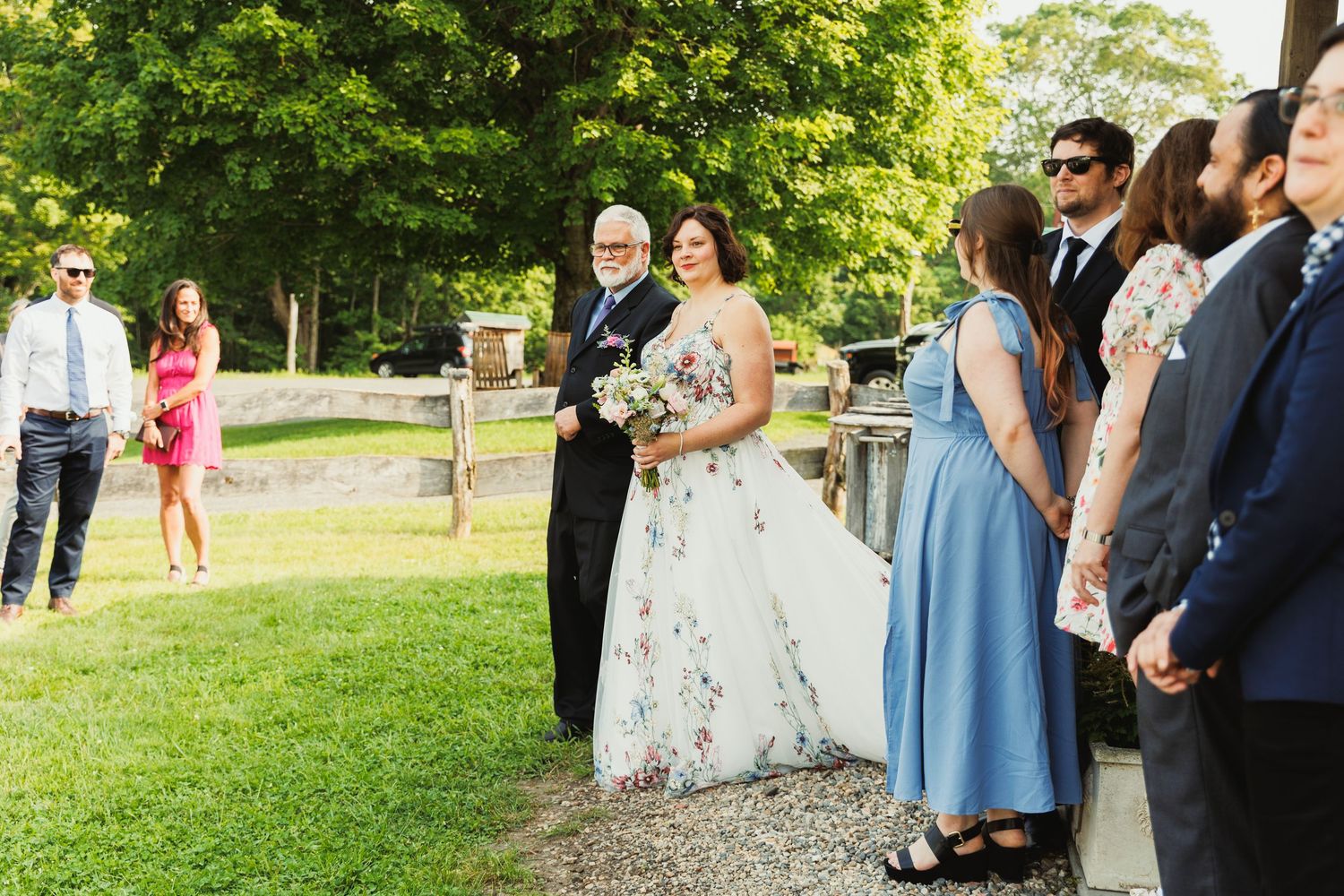 Guests in formal attire standing together outdoors during a summer event.