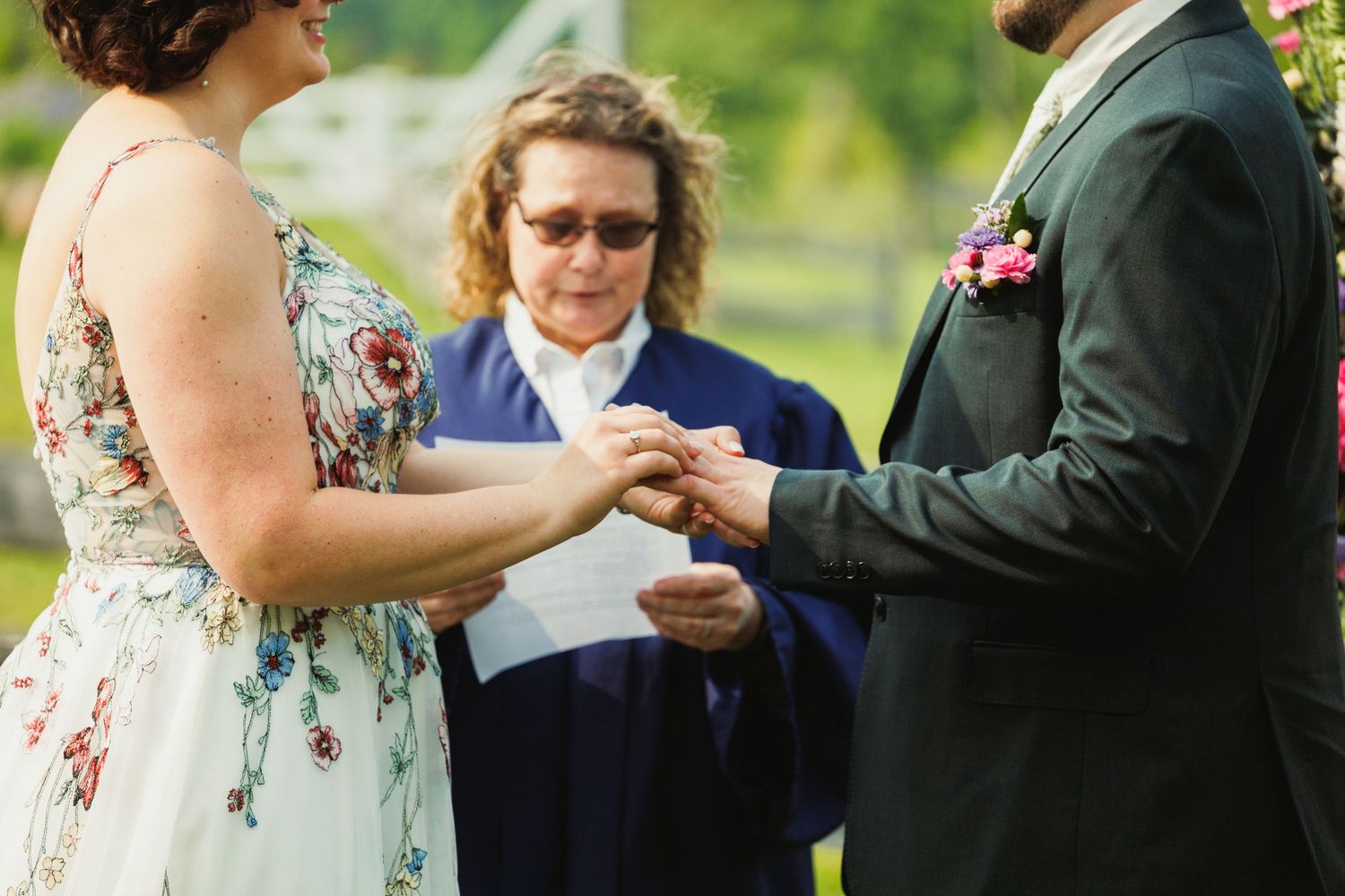Wedding ceremony participants stand at rustic wooden altar during vow exchange.