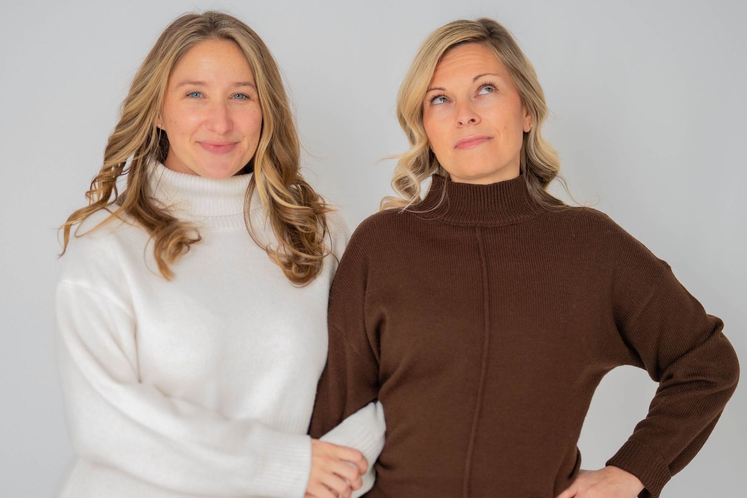 Two people modeling turtleneck sweaters in white and brown.