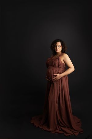 A figure in a flowing brown dress poses gracefully against a dark background in a series of artistic portraits.