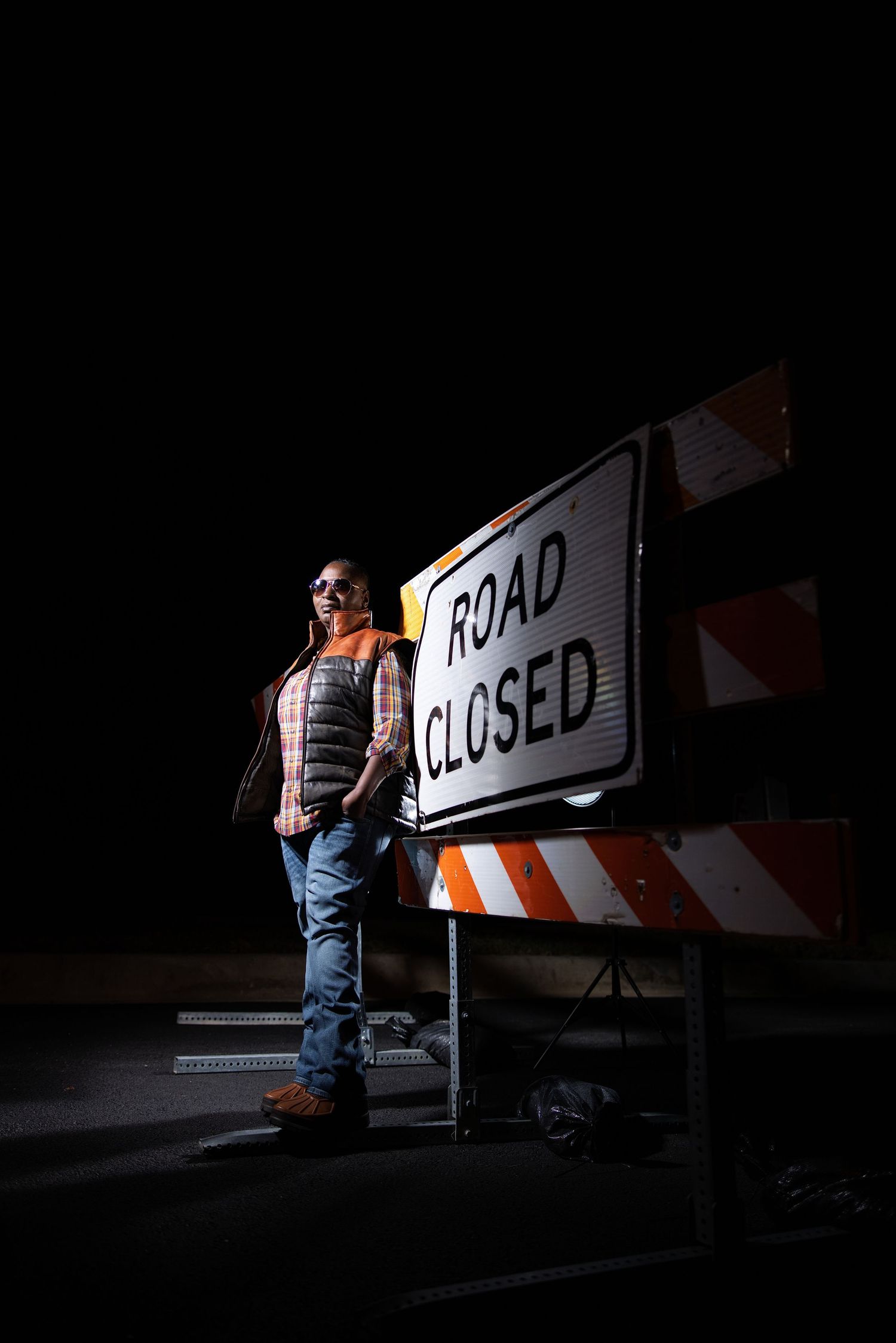 Construction worker near road closed sign in dark nighttime setting.