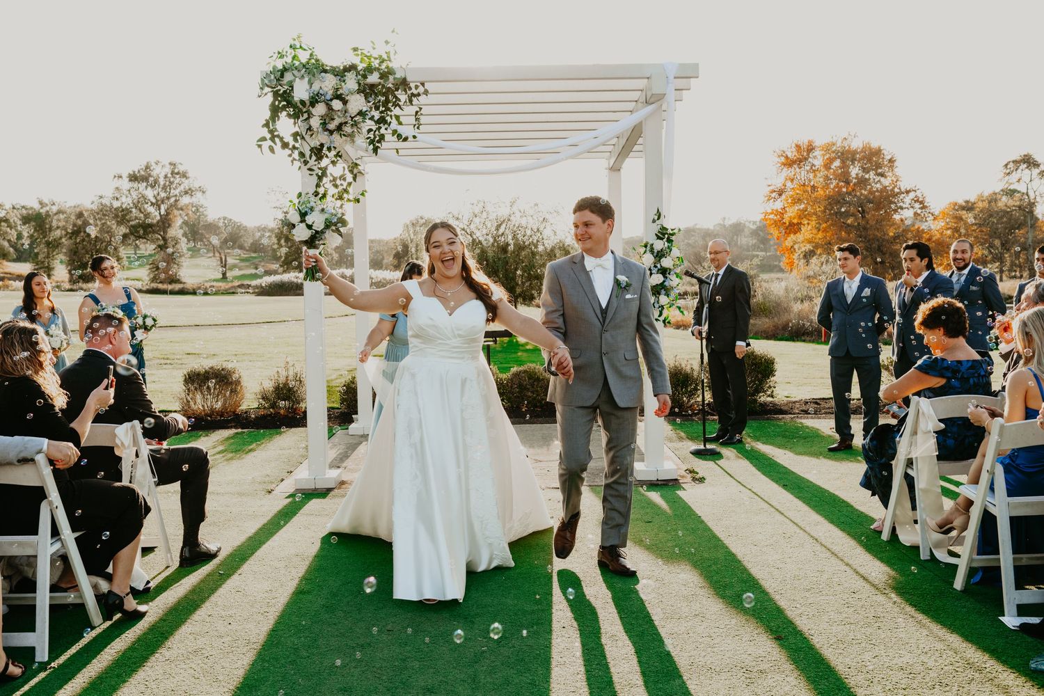 Bride and groom walk hand-in-hand after saying their IDOS in the golf course