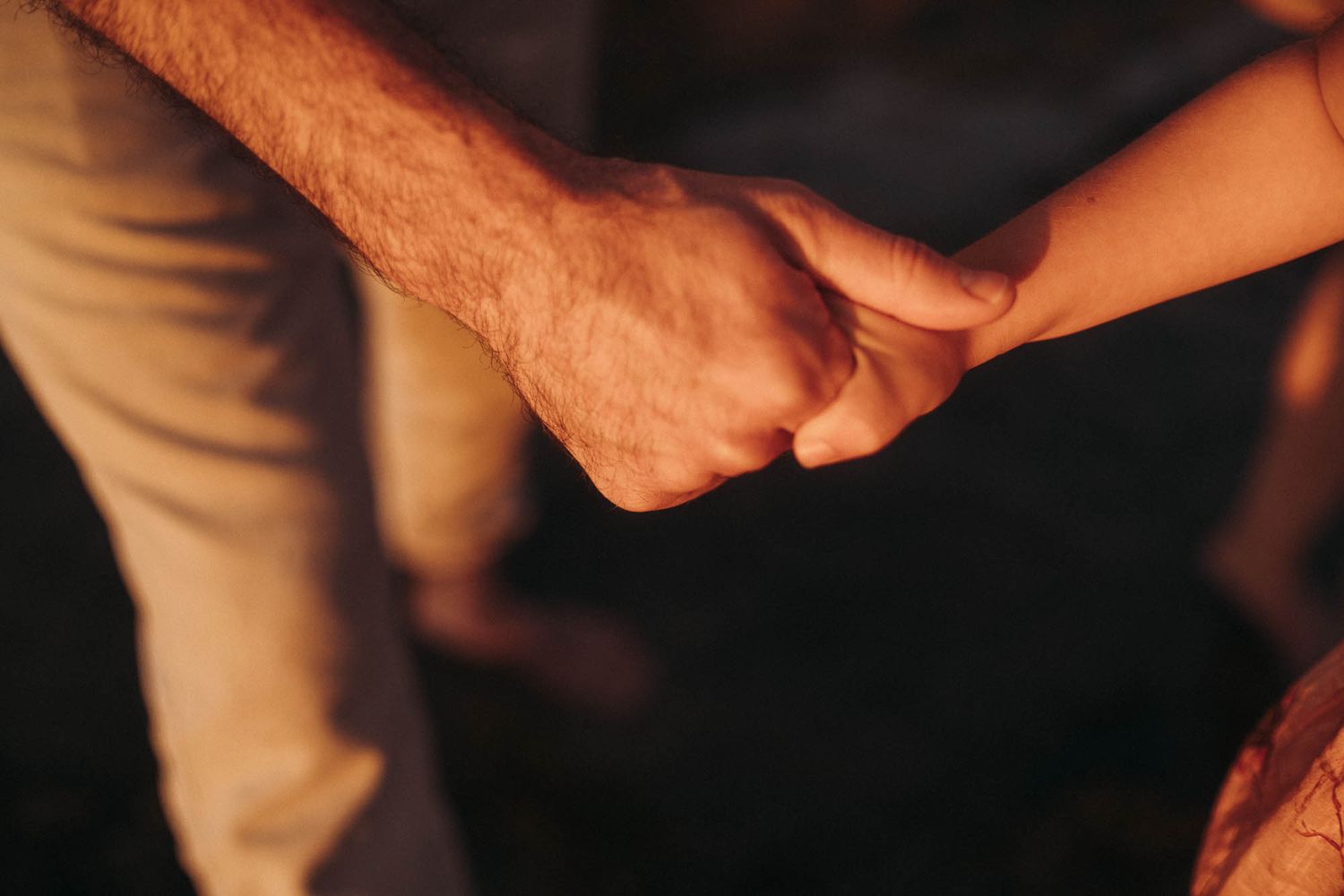 Hands gently hold and position a doll against a shadowy backdrop.