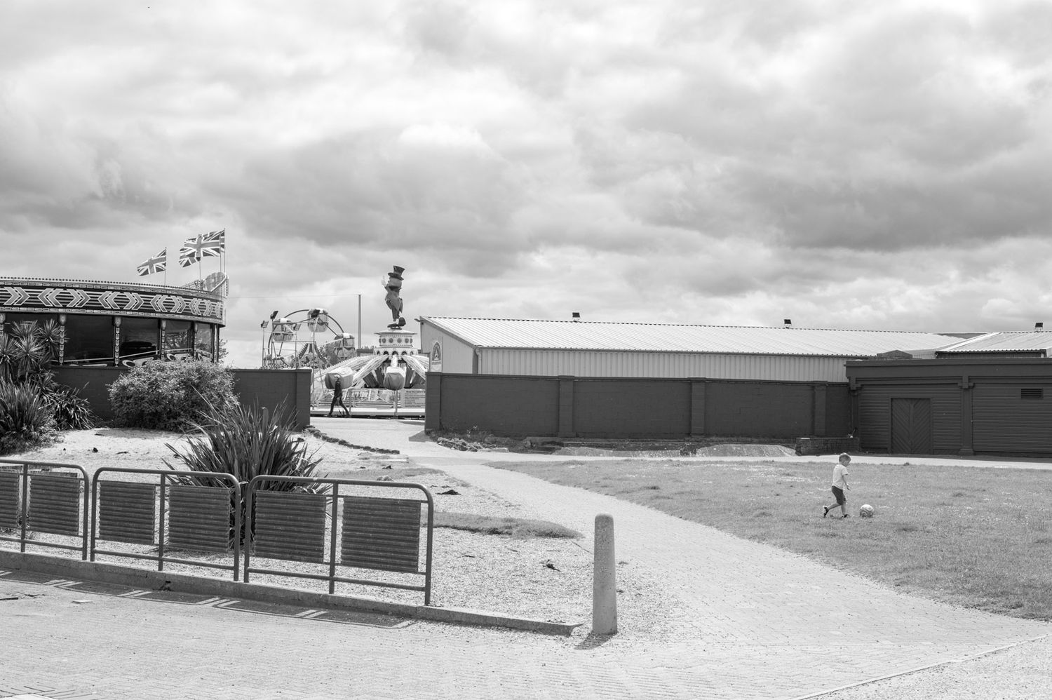 A panoramic black and white view of a mid-century suburban shopping center with parked cars and storefronts.