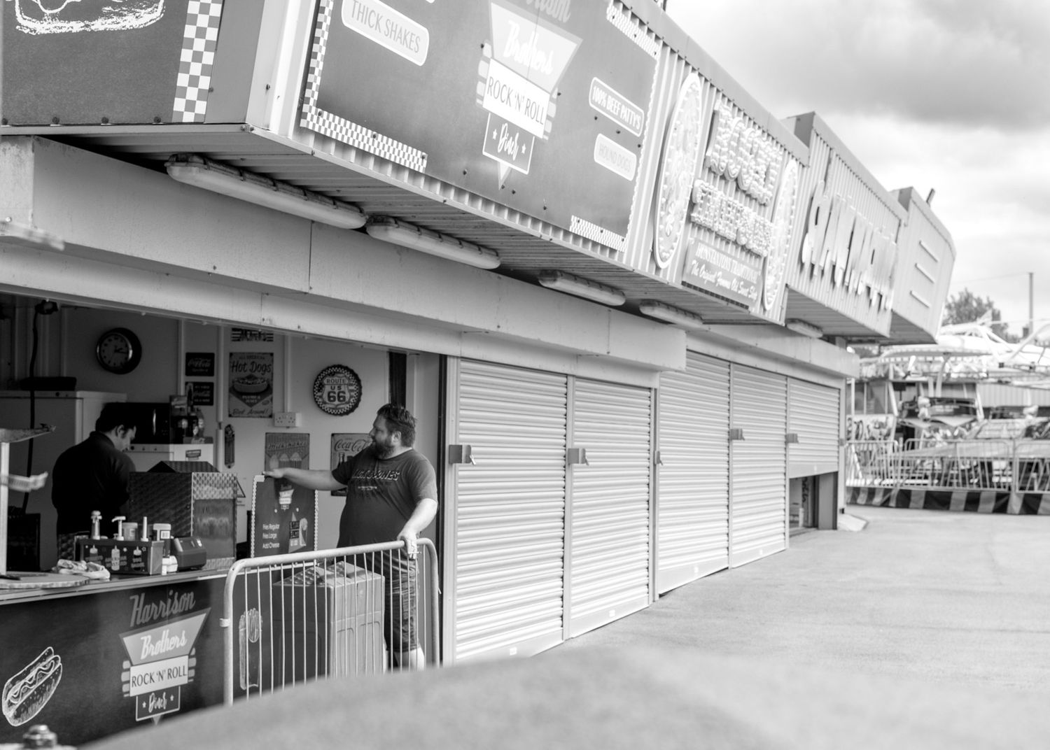 Black and white panoramic view of closed storefronts and empty sidewalks in a shopping center.