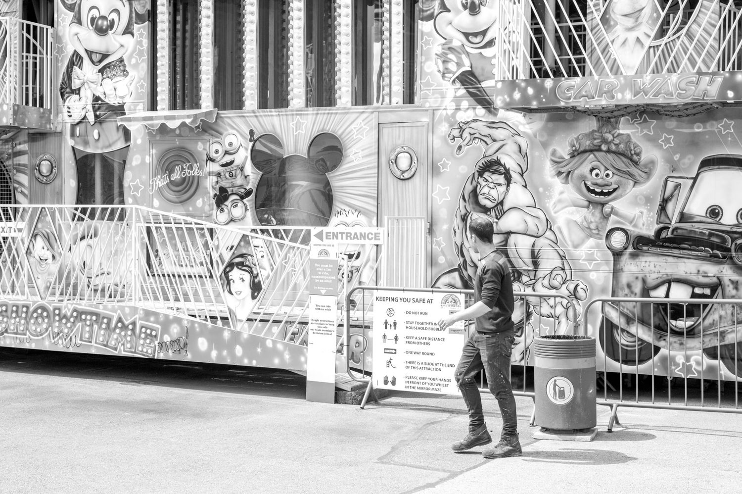 Black and white photo of a person standing near a Disney-themed storefront with Mickey Mouse decorations and displays.
