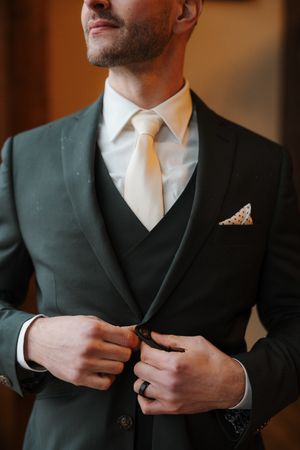 Close-up series of someone in a dark suit adjusting their jacket buttons in a formal setting.