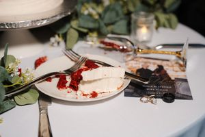 Multiple plates with cake remnants and red accents arranged on a white tablecloth.