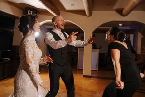 People dancing and having fun at a wedding reception on a wooden dance floor under exposed ceiling beams.