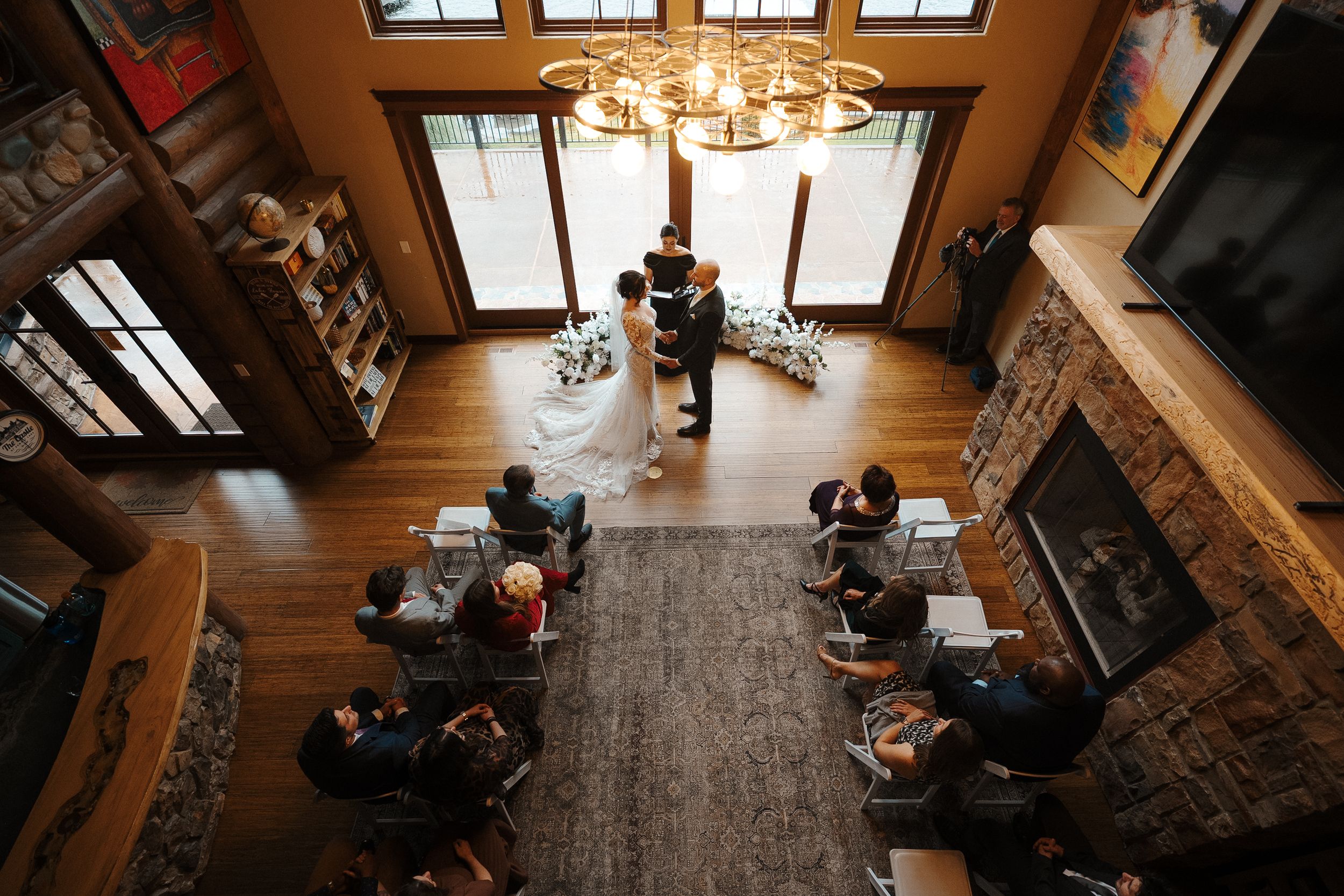 Elegant rustic wedding venue interior with exposed wooden beams and chandeliers creating a warm, romantic atmosphere.