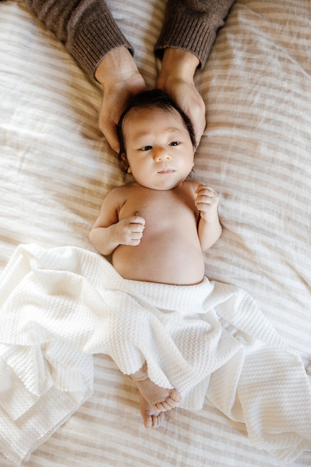 A newborn baby's head is cradled in his dad's hands during his in-home newborn photography session