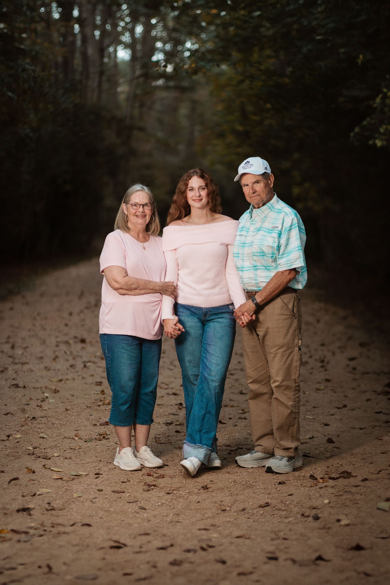 Three people walking and talking together on a dirt path through a wooded area on an autumn day.