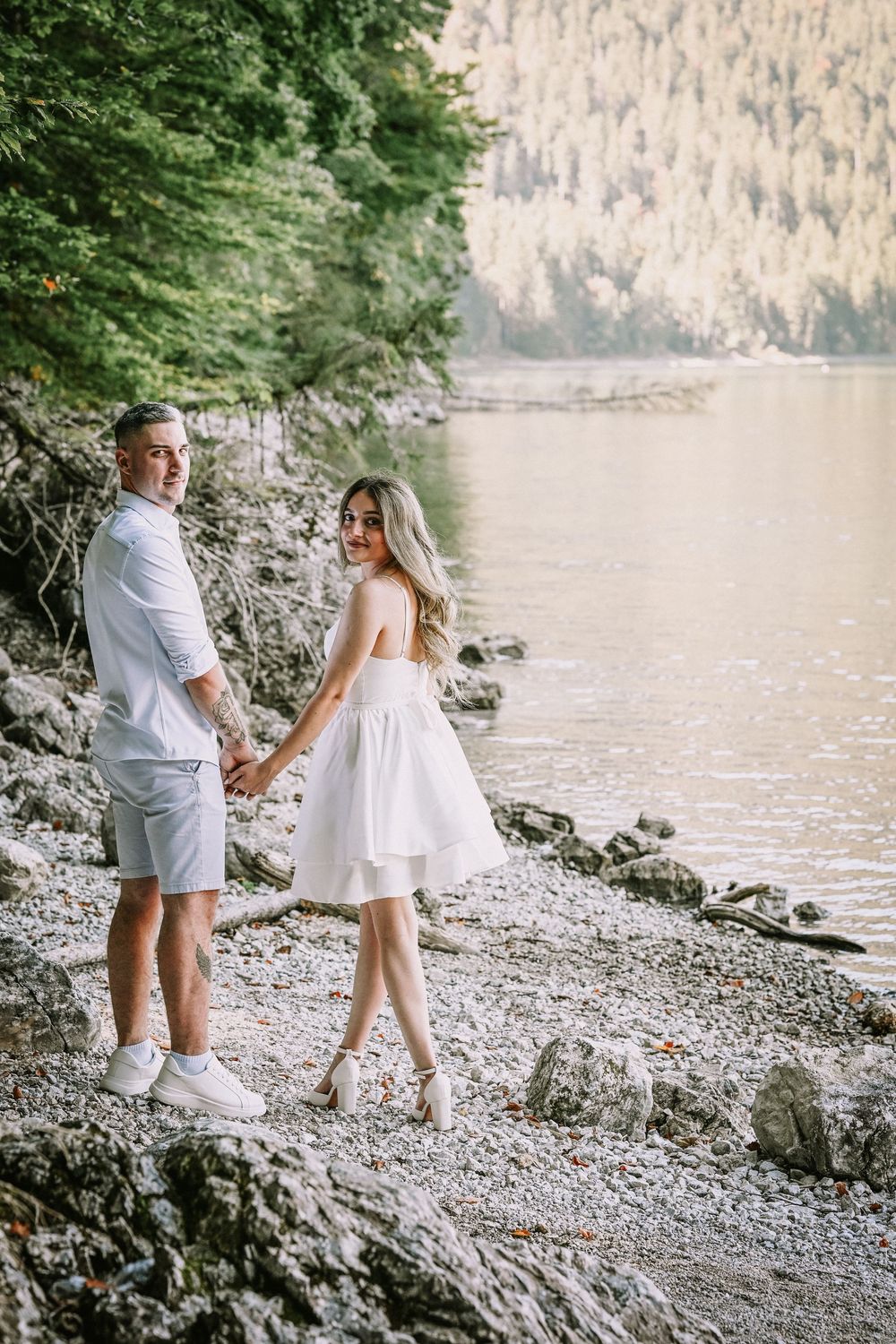 Engagement photo sequence on a rocky beach with mountains and lake in the background.