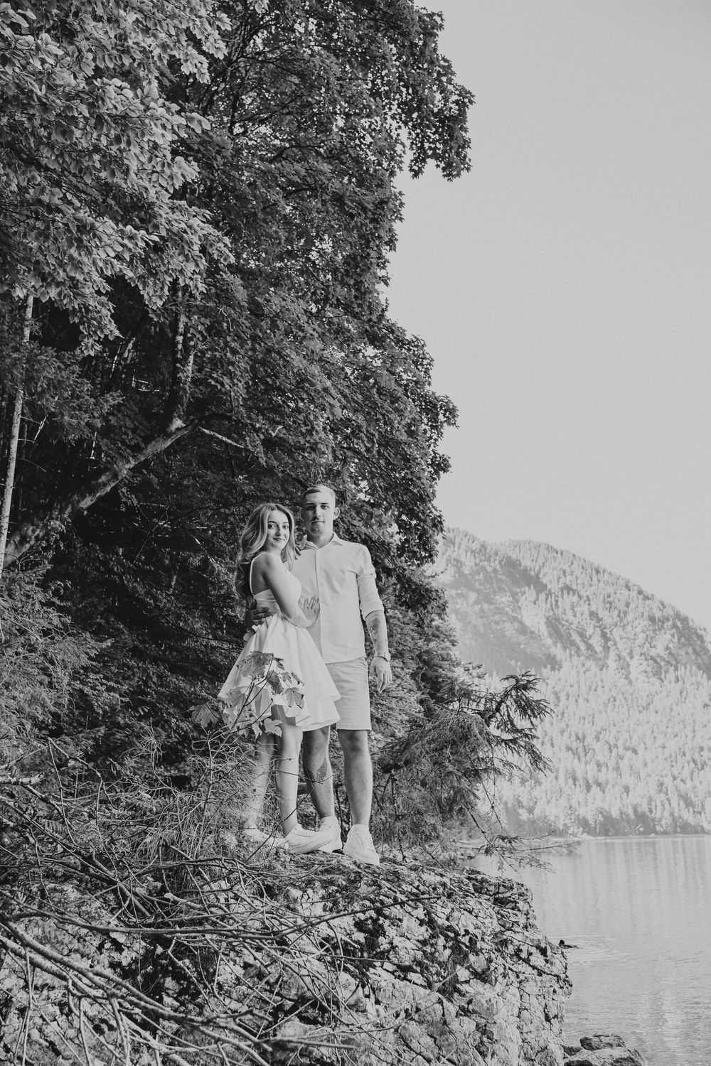 Black and white photo series of a couple walking along a scenic lakeside path.