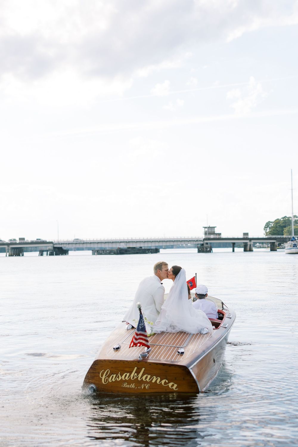 Classic wooden Casablanca boat floating on calm waters with American flag. NC WEDDING PHOTOGRAPHER