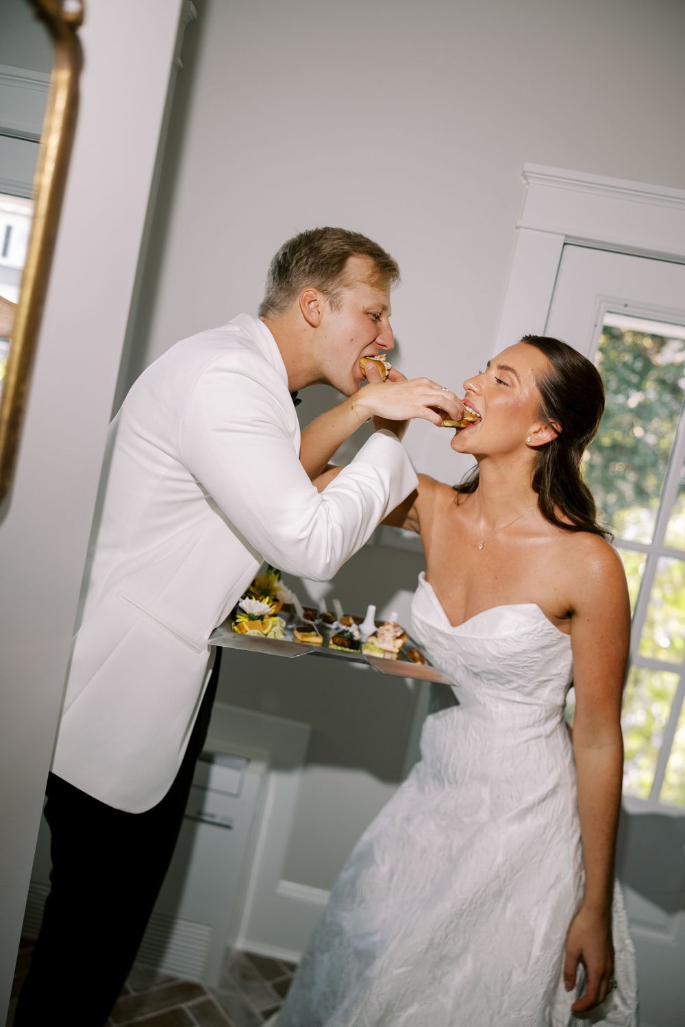 Newlywed couple shares a playful moment feeding each other cake at their wedding reception.NC WEDDING PHOTOGRAPHER