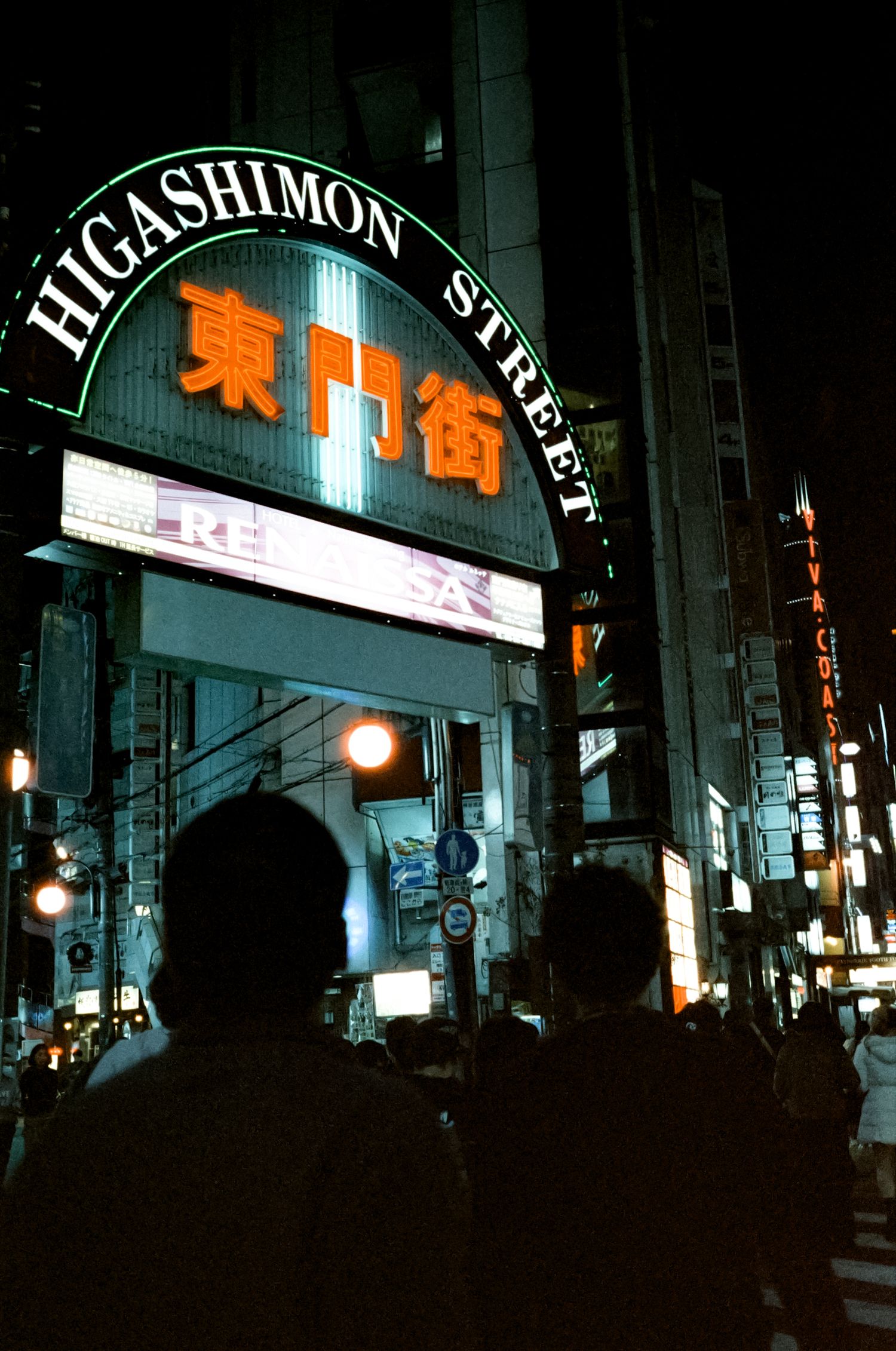 Dimly lit Japanese street at night with glowing lanterns and neon signs illuminating the narrow alleyway.
