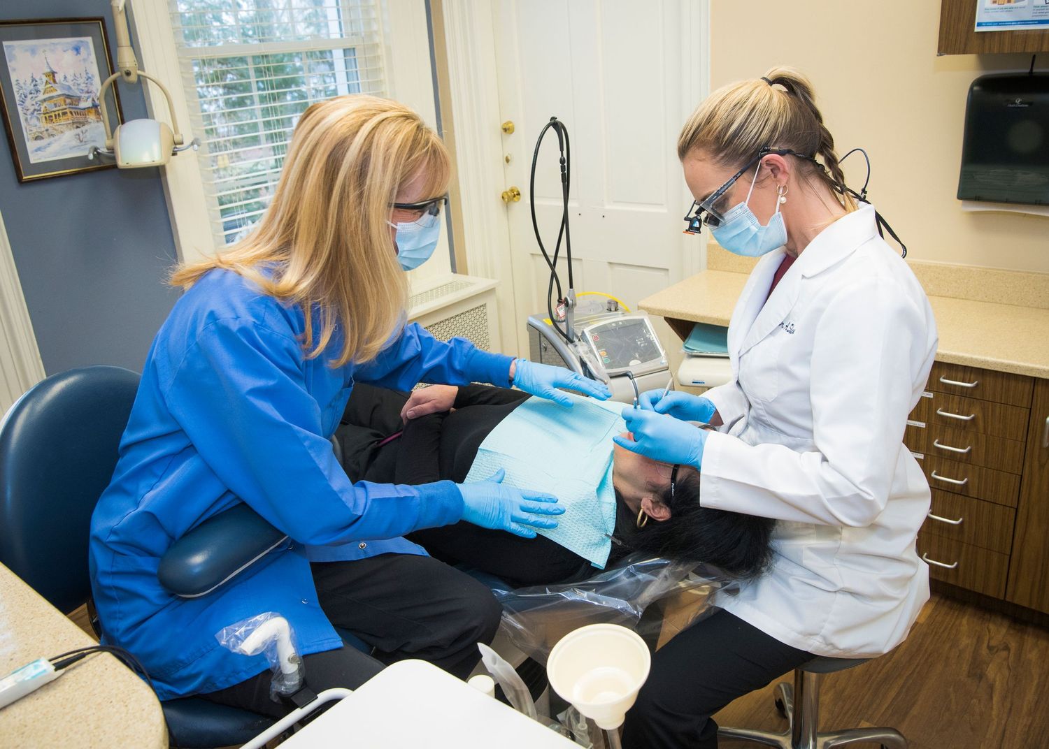 Healthcare professionals in protective gear perform a dental examination in a modern medical office setting.
