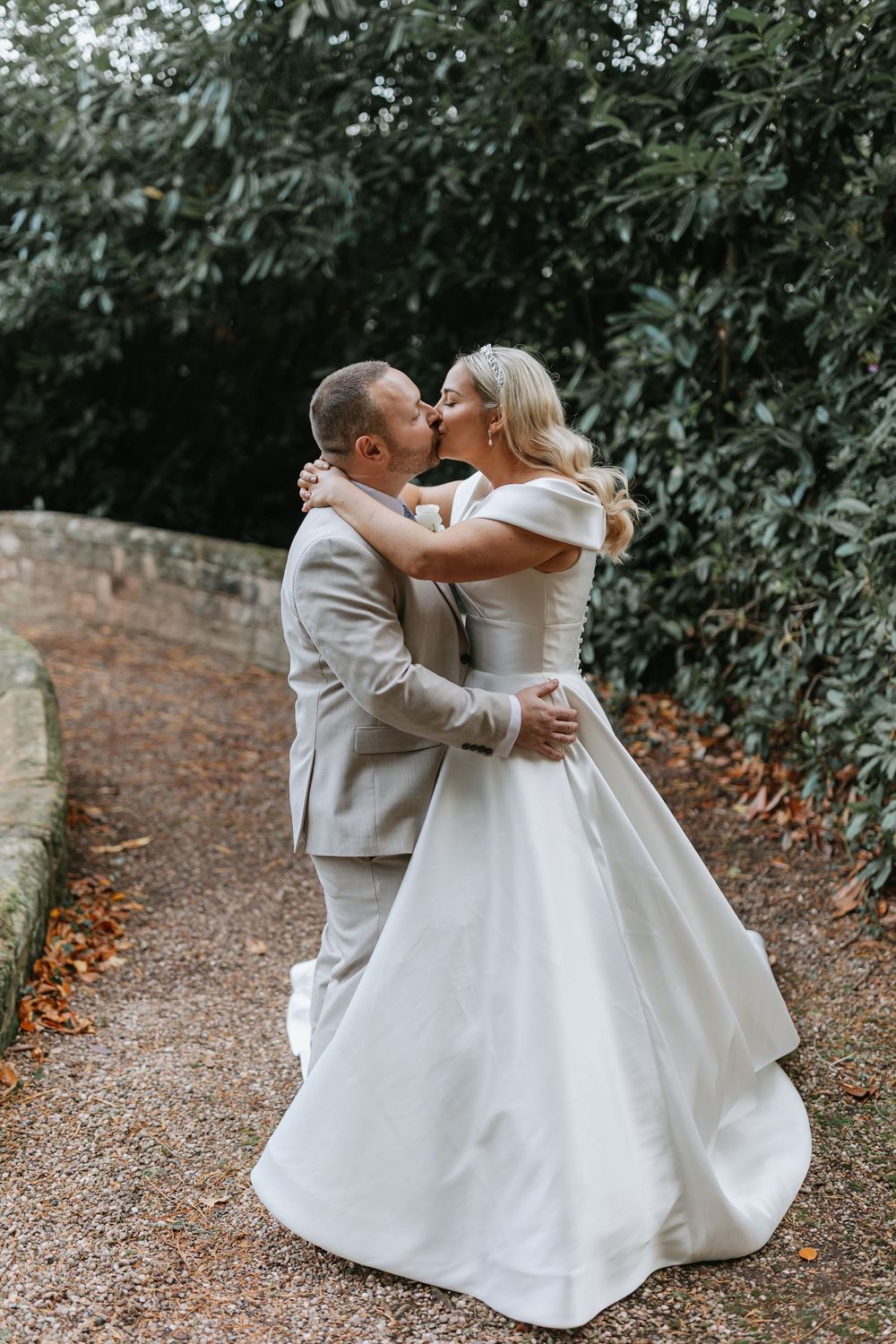 A wedding couple shares an intimate dance moment on a garden path surrounded by autumn foliage.