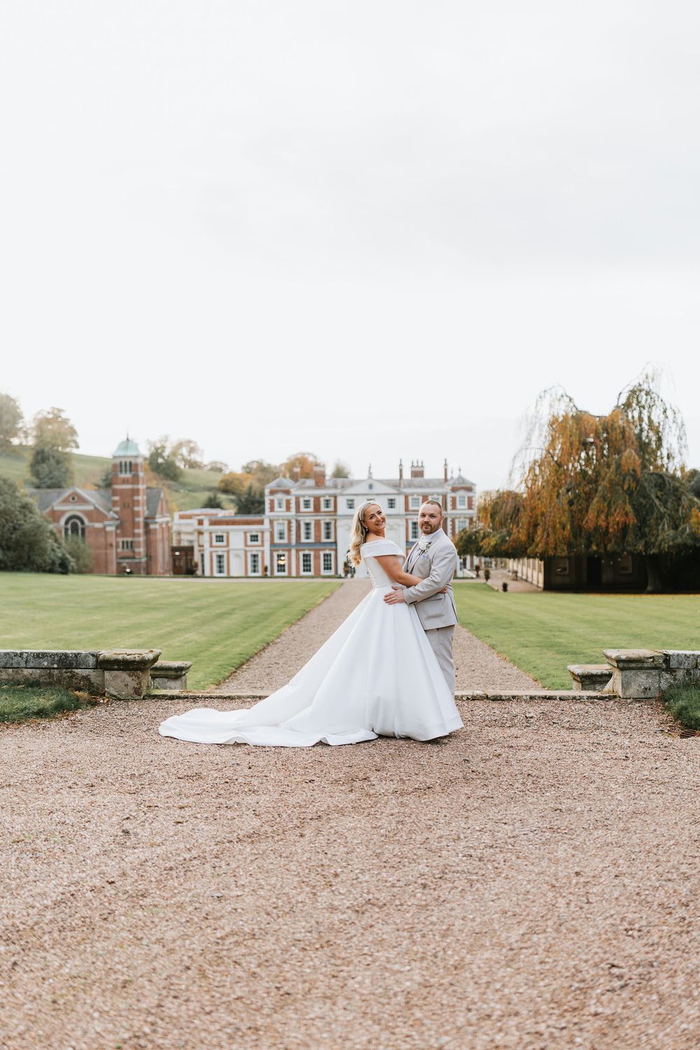 A wedding gown twirls on a gravel driveway with a grand historic mansion in the background.